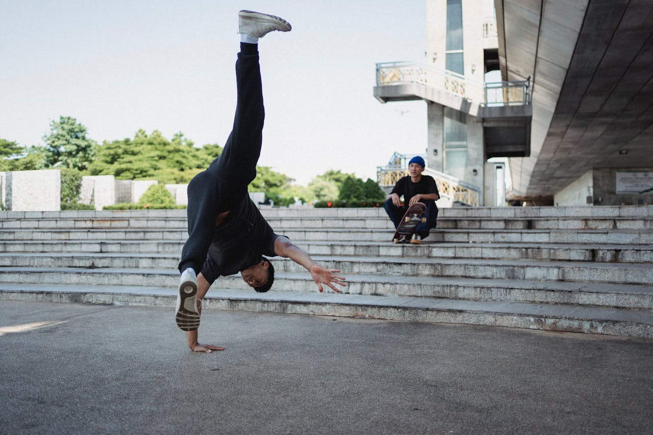 A talented breakdancer performs a one-handed handstand in an urban skate park, showcasing balance and energy.