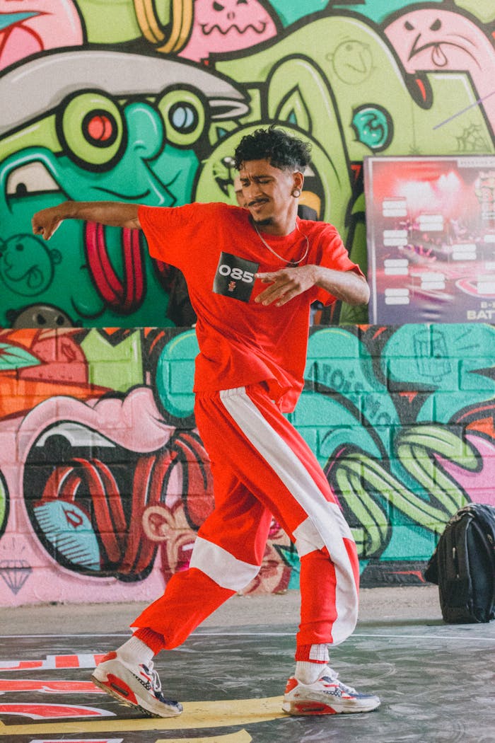 A hip hop dancer in a vibrant graffiti-decorated space, showcasing dynamic movement in red attire.
